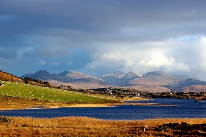 A mountain range across a bog lake in autumn colour under a heavy sky