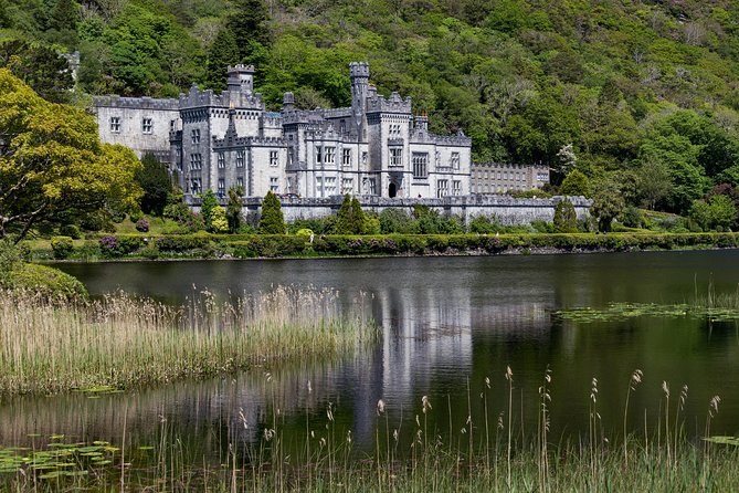 Kylemore Abbey across reeds and dark water at the edge of the lough