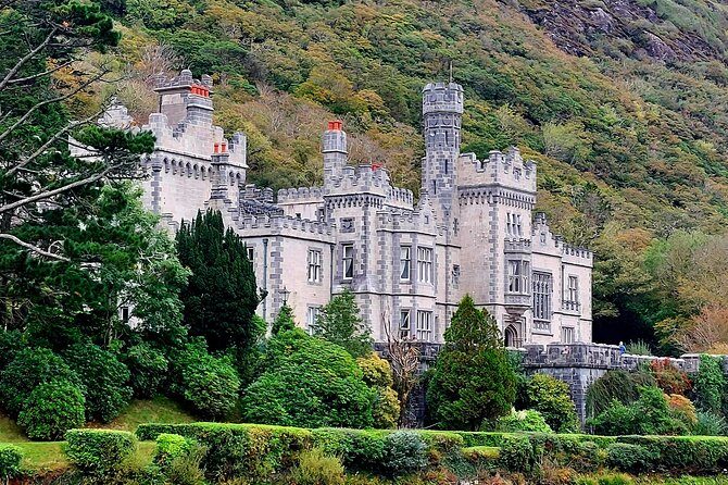 The abbey's turrets rising above clipped shrubs, with the mountain behind
