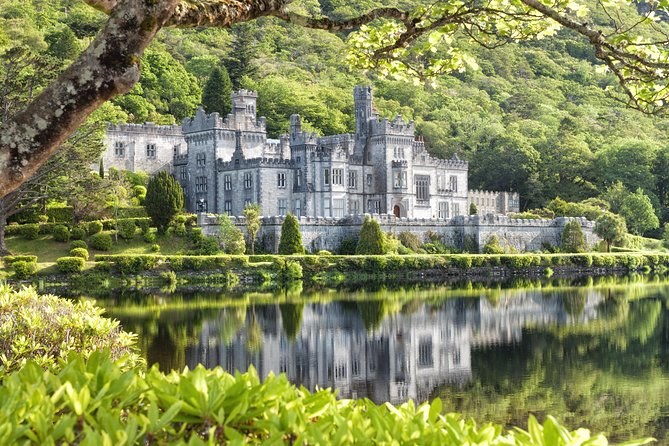 Kylemore Abbey seen across the lough through overhanging branches